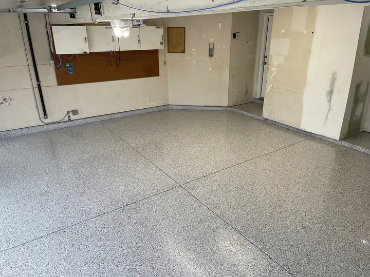 Two-car garage with a gray flake floor and a coated stem wall border